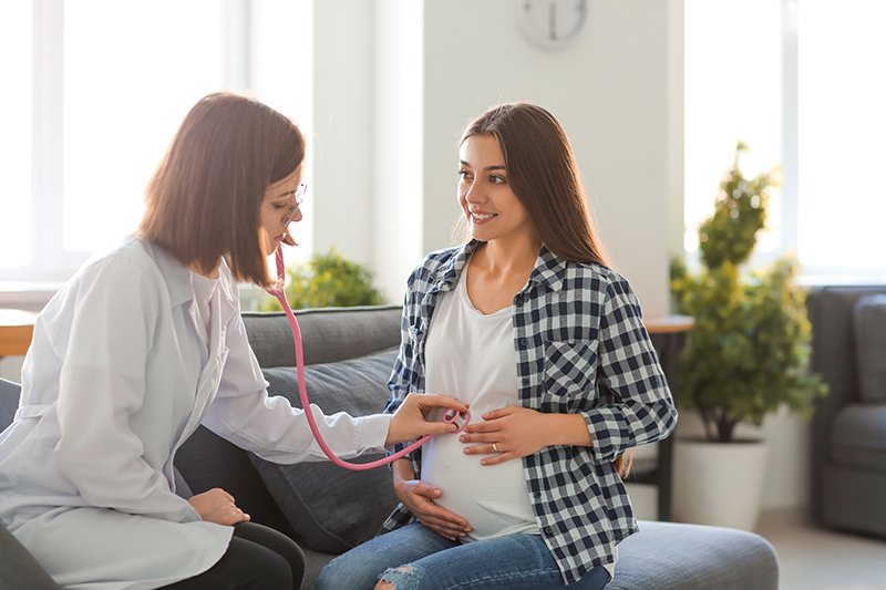 Young doctor examining pregnant woman in clinic
